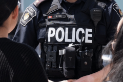 Nine charged after two-year York police probe targets illegal gambling networks. York Regional Police officer wearing tactical vest marked “POLICE” speaks with two civilians during an outdoor interaction.