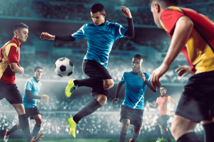 UK targets unlicensed gambling sponsors in major sports crackdown. Soccer players in a packed stadium compete for the ball, with a player in a blue jersey leaping mid-air to control it while defenders in red and yellow close in.