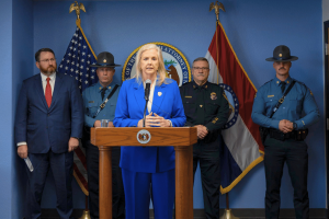 Missouri Attorney General speaks at press conference on illegal gambling machines crackdown with law enforcement officials and state flags behind podium