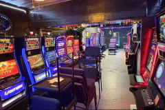 Interior of illegal gambling room in San Antonio with rows of slot machines, chairs, and neon lights during Bexar County raid