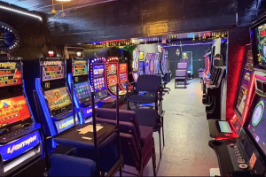 Interior of illegal gambling room in San Antonio with rows of slot machines, chairs, and neon lights during Bexar County raid