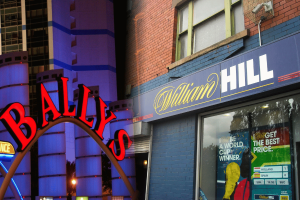 Bally's casino sign and William Hill betting shop storefront, illustrating gambling industry takeover talks involving Evoke plc brands.