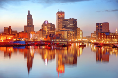 Rhode Island skyline at sunset reflected on the Providence River, highlighting downtown Providence as lawmakers consider expanding the state's sports betting market and ending its sportsbook monopoly.