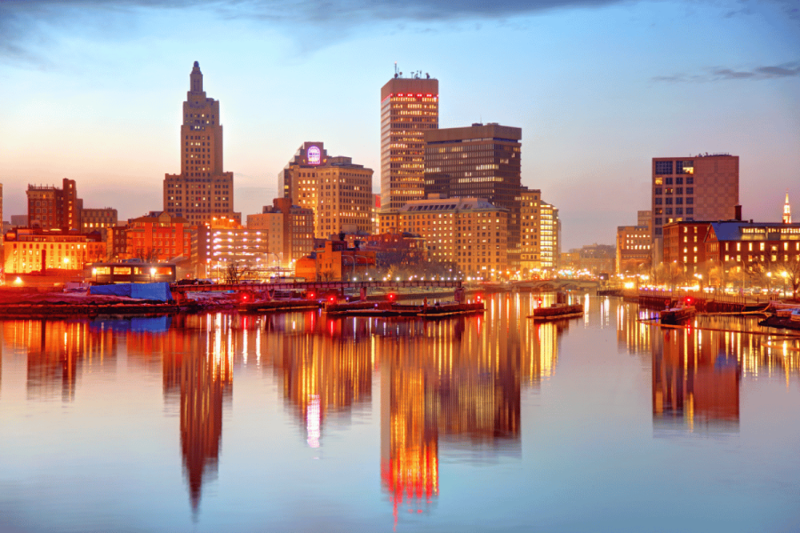 Rhode Island skyline at sunset reflected on the Providence River, highlighting downtown Providence as lawmakers consider expanding the state's sports betting market and ending its sportsbook monopoly.