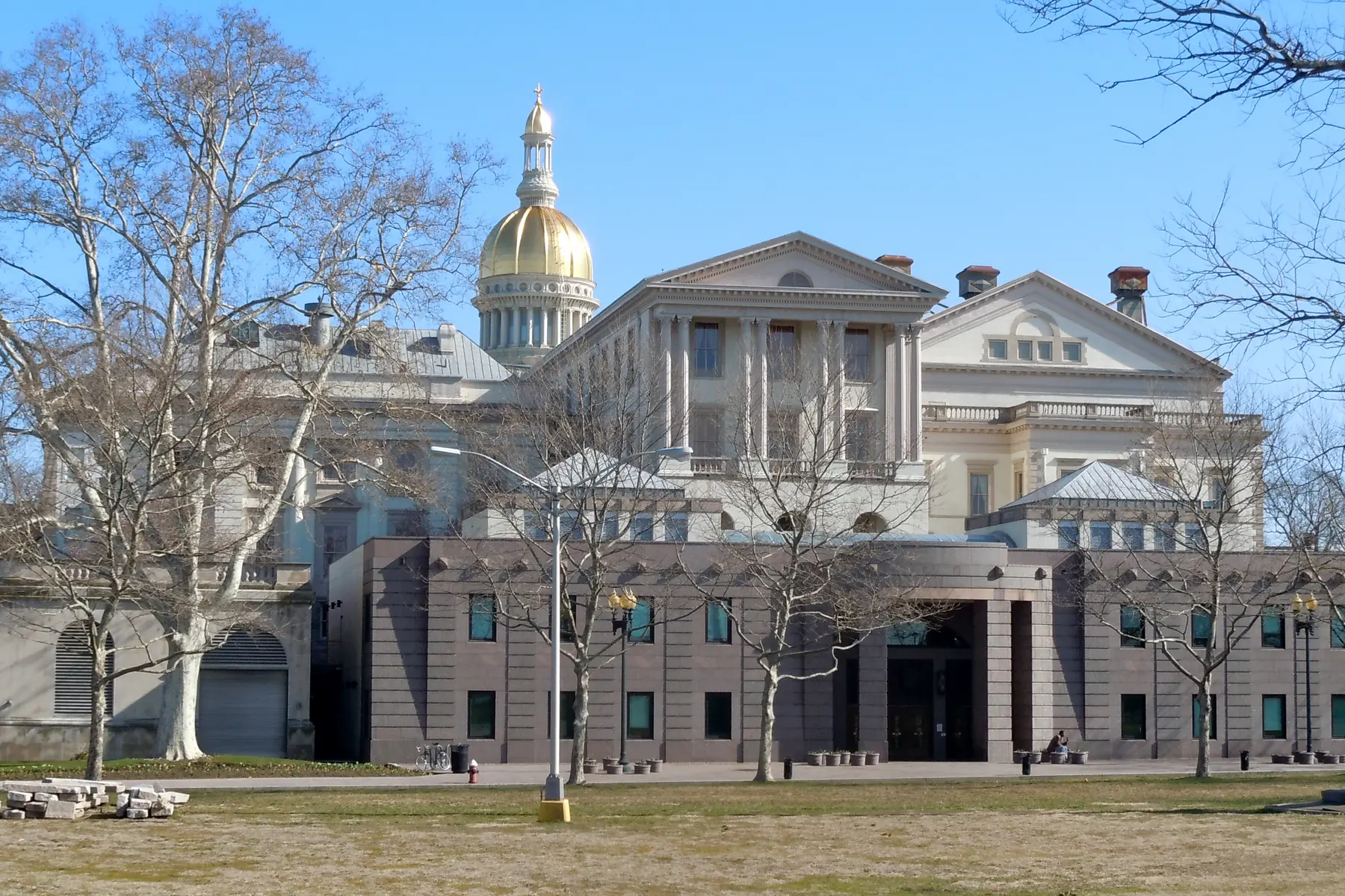 Exterior view of the New Jersey State House in Trenton, featuring its golden dome and neoclassical architecture.