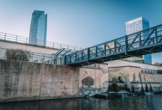 Oklahoma City canal with murals, a footbridge and downtown towers